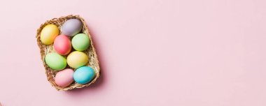 Renkli arka planda dokuma sepetinde çok renkli Paskalya yumurtaları. Pastel renginde Paskalya yumurtası. Kopyalama alanı olan tatil kavramı.