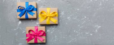 El işi kağıdına sarılı, masa arkasında renkli bir fiyonk olan tatil hediyesi kutusu. Üst görünüm, düz görünüm, kopyalama alanı.