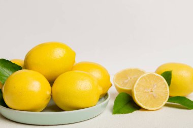 Taze kesilmiş limon ve tüm limonları renkli arka planda yuvarlak tabakta. Yemek ve içecek malzemeleri hazırlanıyor. Sağlıklı beslenme teması üst görünüm kopyalama alanı.