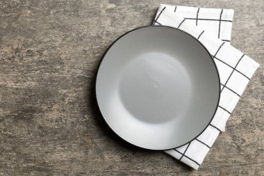 Renkli arka planda üst görünüm yiyecek için masa örtüsü üzerindeki boş yuvarlak gri tabak. Tasarımınız için boşluk olan peçeteye boş tabak.