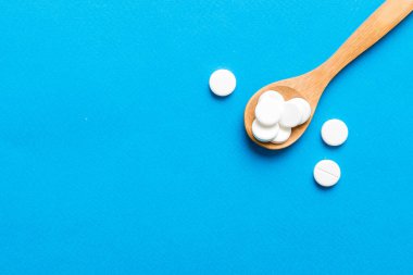 Renkli arka planda bir yığın beyaz hap. Tabletler masaya saçılmış. Kırmızı yumuşak jelatin kapsül yığını. Vitaminler ve beslenme takviyeleri konsepti.