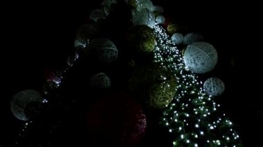 Gece şehrindeki büyük bir Noel ağacının parlak çelenkleri ve büyük oyuncakları var..