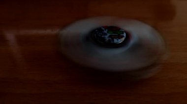 Eski ahşap bir masanın üzerinde dönen dönen bir döner. Fidgeting spinner, dönen el spinner. Gevşemek için oyuncak Bilinen fırıldak.