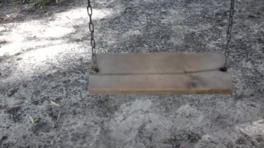 Zincirle asılı boş ahşap salıncak sallanıyor. Yakın çekim salıncaktır..
