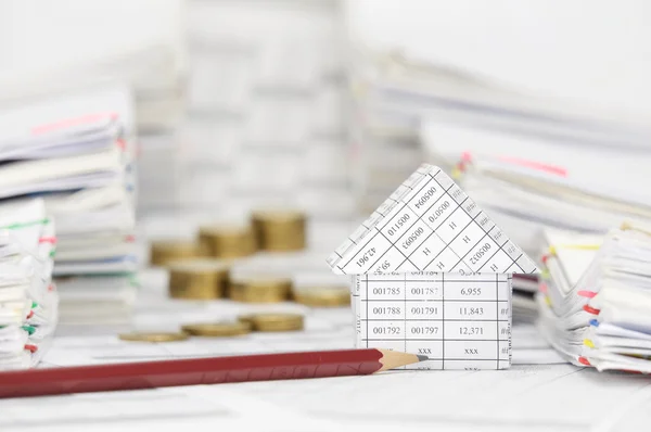 Huis en potlood en vervagen tussen overbelasting papierwerk munten — Stockfoto