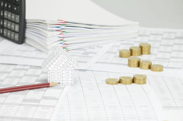 Casa com lápis e passo moedas de ouro em conta financeira — Fotografia de Stock