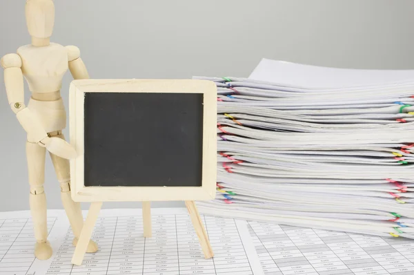 Trä dummy håller tom blackboard på finans konto — Stockfoto