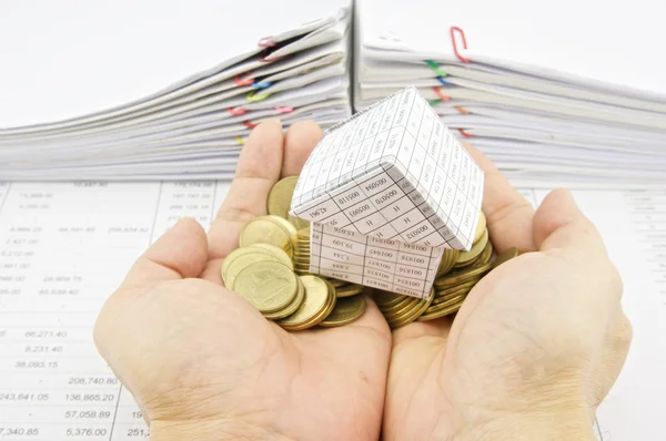 Man met papier huis op stapel gouden munten — Stockfoto