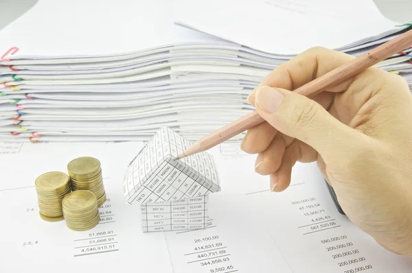 Hombre sosteniendo lápiz sobre la casa en el balance — Foto de Stock