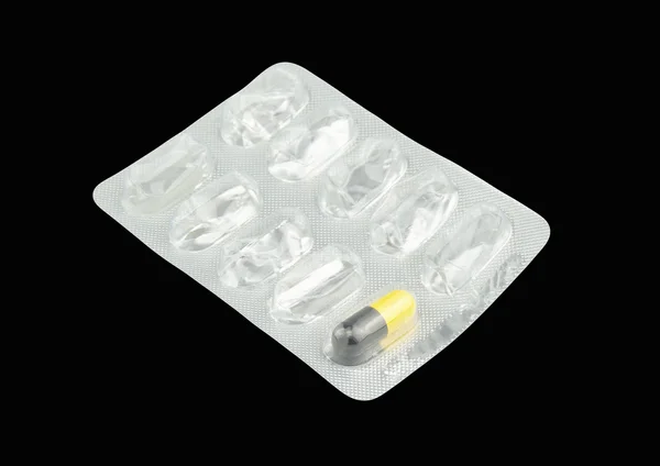 Last black and yellow capsule pill in silver panel isolated — Stock Photo, Image