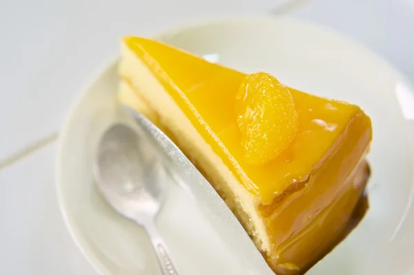 Trancher le gâteau orange dans une assiette en céramique blanche — Photo