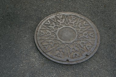 Metal circle of drain water on pavement clipart