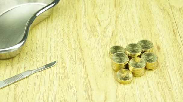 Edelstahlskalpell und Erbrechen-Becken mit Goldmünzen im Zeitraffer — Stockvideo