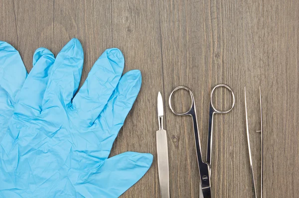 Cerrahi makas gümüş neşter ve forseps mavi lateks eldiven yanında kapatın — Stok fotoğraf