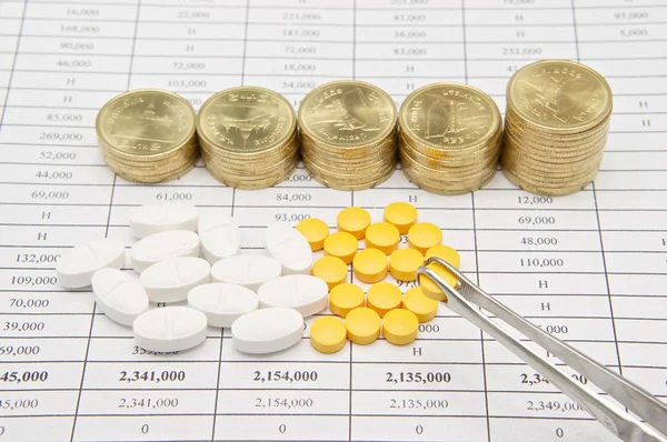 Pinzetten-Prise-Pille mit einem Stapel Goldmünzen — Stockfoto