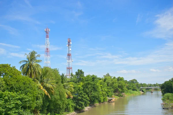 Antenna cellular tower in forest beside river and blue sky — Stock Photo, Image