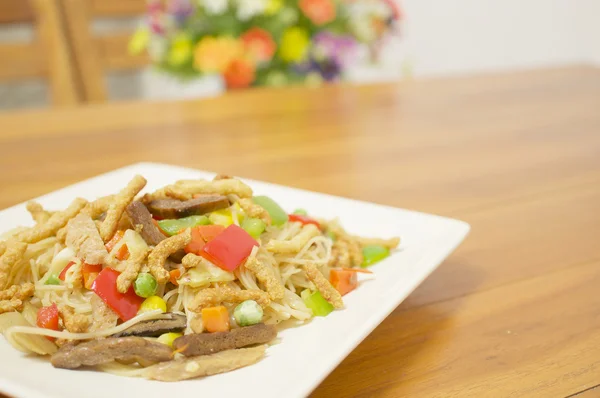 Colorful long life noodle fried on table with blur flower — Stock Photo, Image