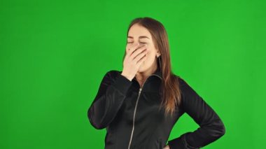 Yorgun bir kız yeşil ekranda esniyor.