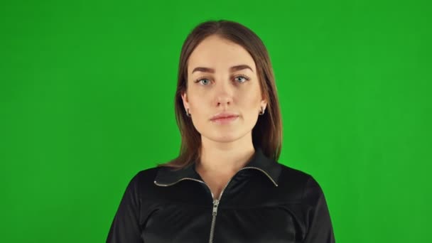 Happy young woman poses for a portrait on green screen. Looks at the camera — Stock Video