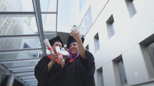 Dva absolventi si berou selfie. Zachycování šťastných chvil. — Stock video