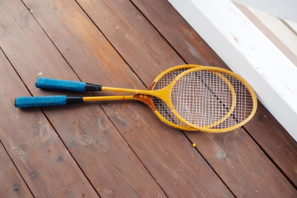 Badminton raketleri ahşap verandada yatıyor.