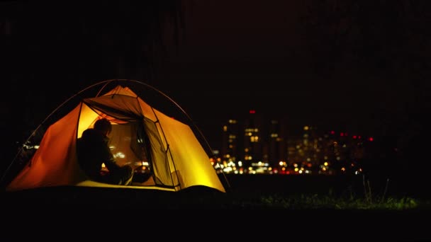 一个年轻人在大城市附近的橙色帐篷里用手机聊天. — 图库视频影像