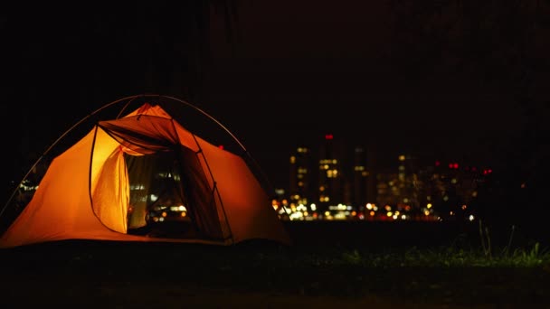 街のナイトライフを背景にオレンジのテント. — ストック動画