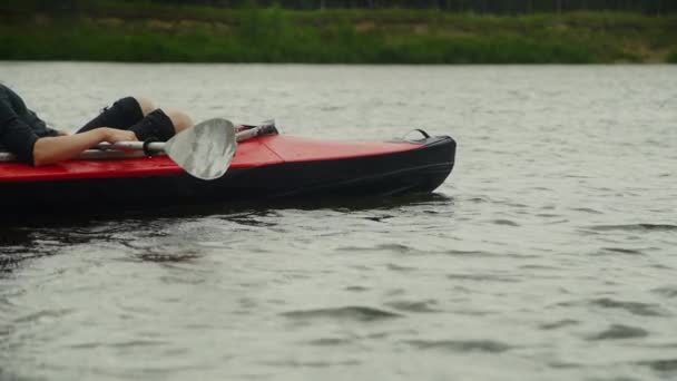 Un joven descansando en un kayak después de remar en el río — Vídeo de stock