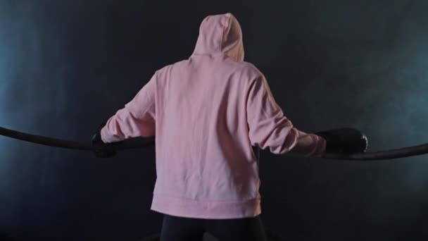 Una luchadora con una sudadera rosa se está calentando agarrándose a las cuerdas — Vídeo de stock