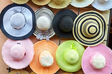 Renkli hasır şapkalar duvarında asılı