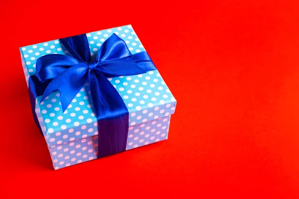 Kırmızı arka planı olan mavi hediye kutusu. Tatil tebrik kartı.. — Stok fotoğraf