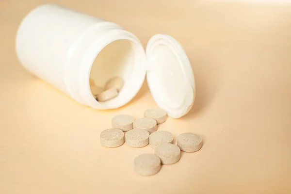 Medicijnfles met tabletten. Pillen van de fles op de perzik achtergrond. Brouwersgist met zink. — Stockfoto