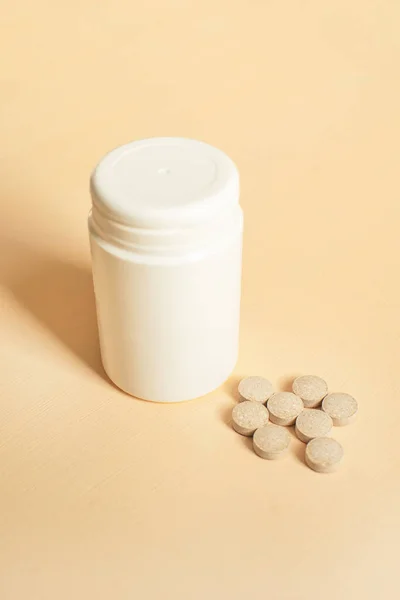 İlaçlı ilaç şişesi. Şeftali arka planında şişeden alınan haplar. Çinko mayalı bira mayası.