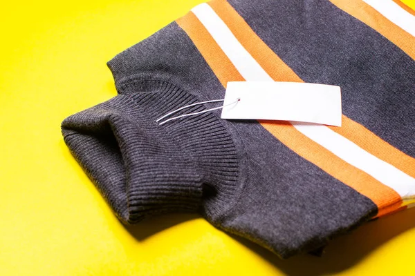 Sarı arka planda turuncu çizgili gri kazak. Alışveriş, indirim, kadın modası..