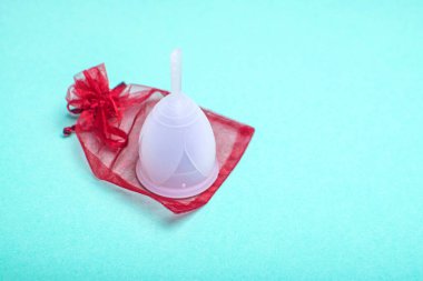 Çevre dostu silikonemenstrüal bardak, yeşil arka planda kırmızı paket. Kadın sağlığına dikkat edin..