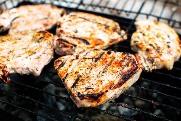 Appetitlich gegrilltes Schweinekotelett auf flammendem Grill. Saftiges Fleisch auf einem Metallständer. — Stockfoto