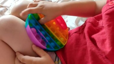 Çocuk parlak gökkuşağı oyuncağı antistresiyle oynuyor. Esnek duyusal stres önleyici oyuncak - popit, basit gamze.