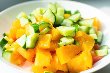 Beyaz tabakta salatalıklı, baharatlı ve yağlı taze sarı domatesler. Lezzetli ve sağlıklı yiyecek kavramı.