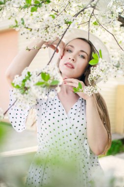 Parkta poz veren güzel bir kız ya da çiçek açan bir elma ve kiraz ağacının yanında..