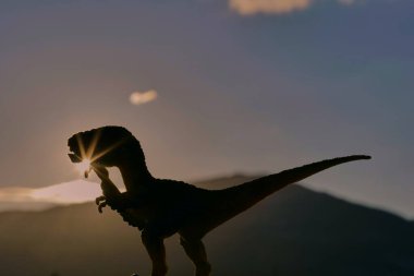 Günbatımı arka planında dinozor silueti
