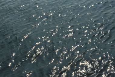 Güneş ışınları berrak mavi bir suda parıldıyor.