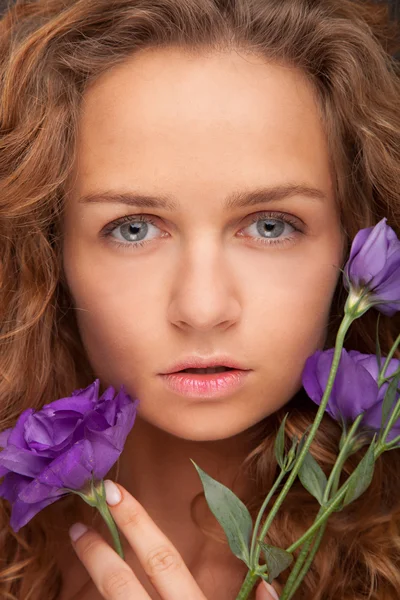 Mooi meisje met violette bloemen. — Stockfoto