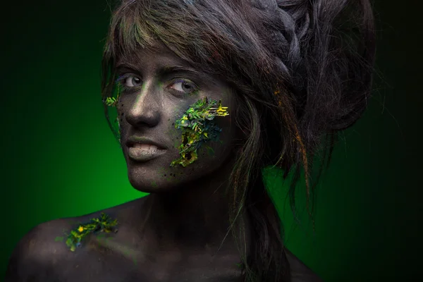 Woman with black face and green face art — Stock Photo, Image