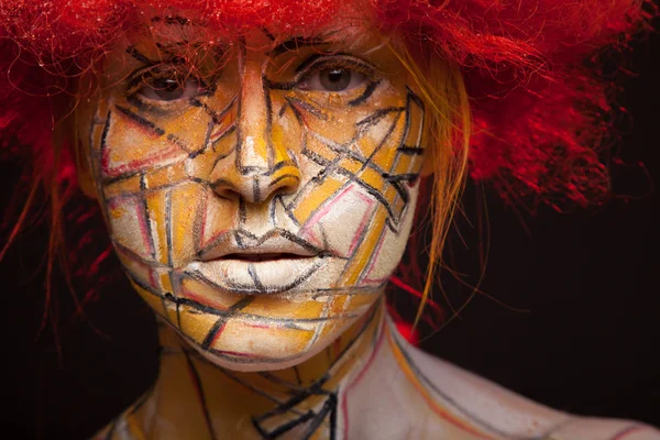 Ragazza in una parrucca rossa e brillante arte viso — Foto Stock