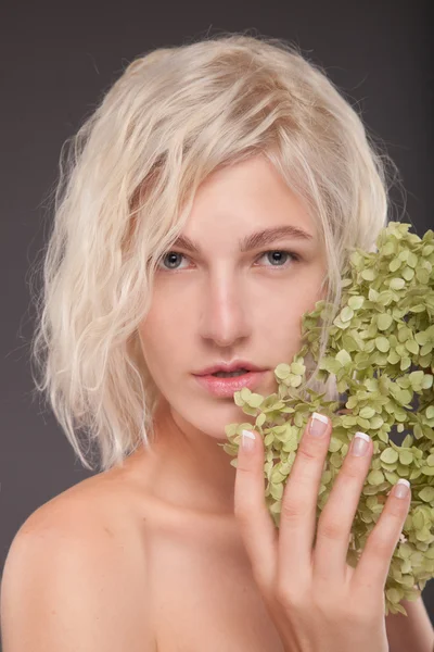 Blond dziewczynka z zielone kwiaty — Zdjęcie stockowe