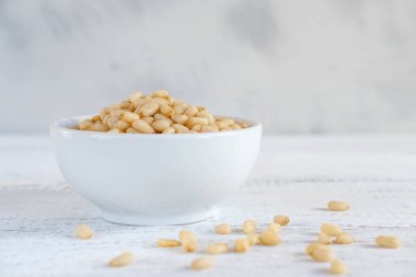 Tahta tepside beyaz bir kasede taze, lezzetli çam fıstığı. Sağlıklı gıda ve beslenme konsepti