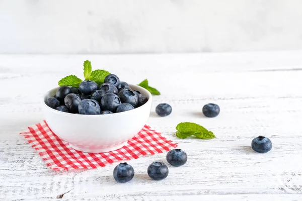 Kırsal bir masada bir kasede sulu ve taze yaban mersini. Sağlıklı yaz hasadı kavramı