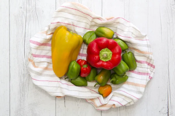 Paprika in verschiedenen Farben auf rustikalem Tuch und hölzernem Backgro — Stockfoto