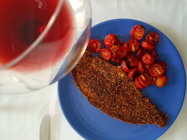 Datterini domatesli bir tabakta kılıçbalığı ve bir bardak beyaz şarap.