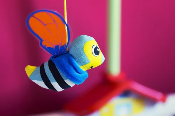 Little bee hanging above baby bed — Stock Photo, Image